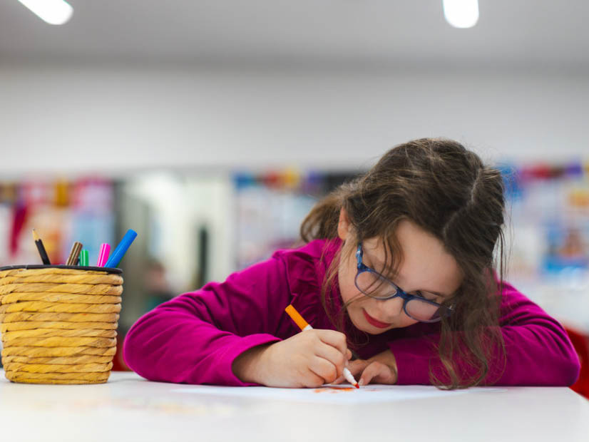 Girl sitting down at table drawing at Barton Outside School Hours Care