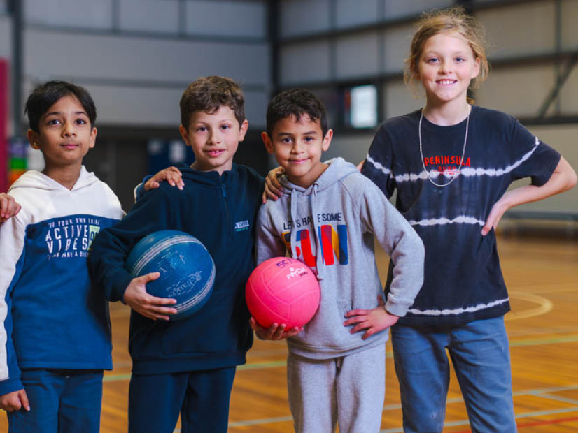 OSHC Kids standing in line on a court holding balls